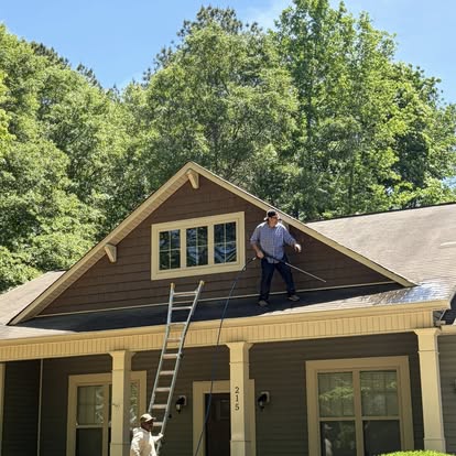 Worker on the roof of a craftsman-style home performing gutter cleanout